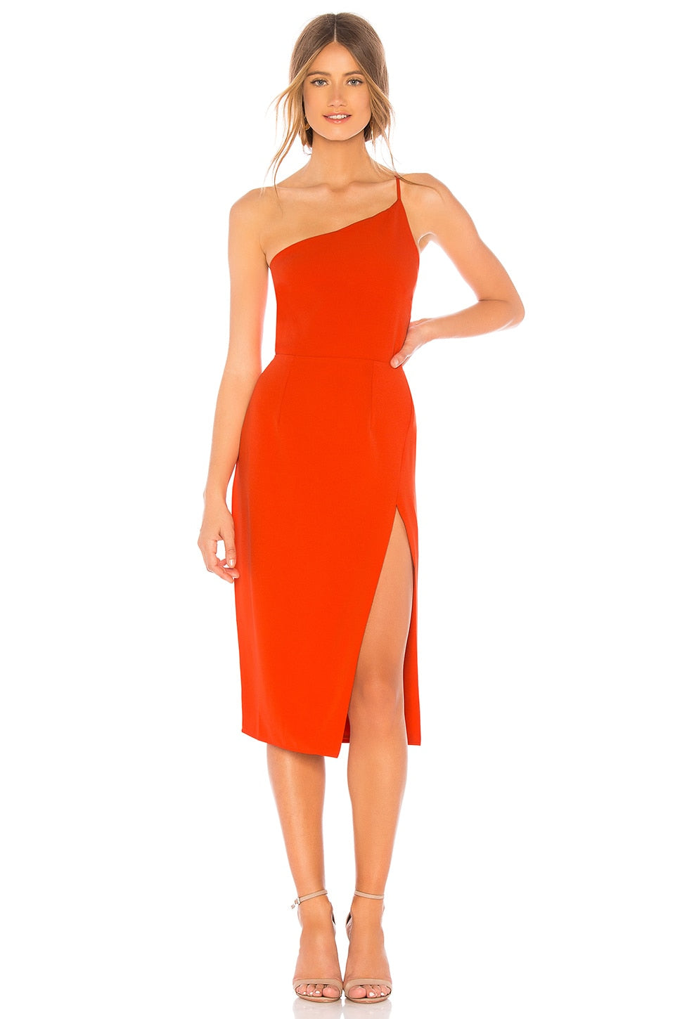 Woman wearing a bright orange one-shoulder dress with a slit on a white background