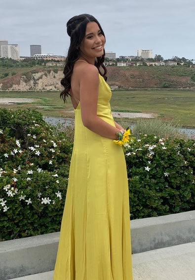 Woman in a yellow dress holding flowers with a scenic background