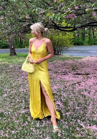Woman in a yellow dress standing in a park with cherry blossoms